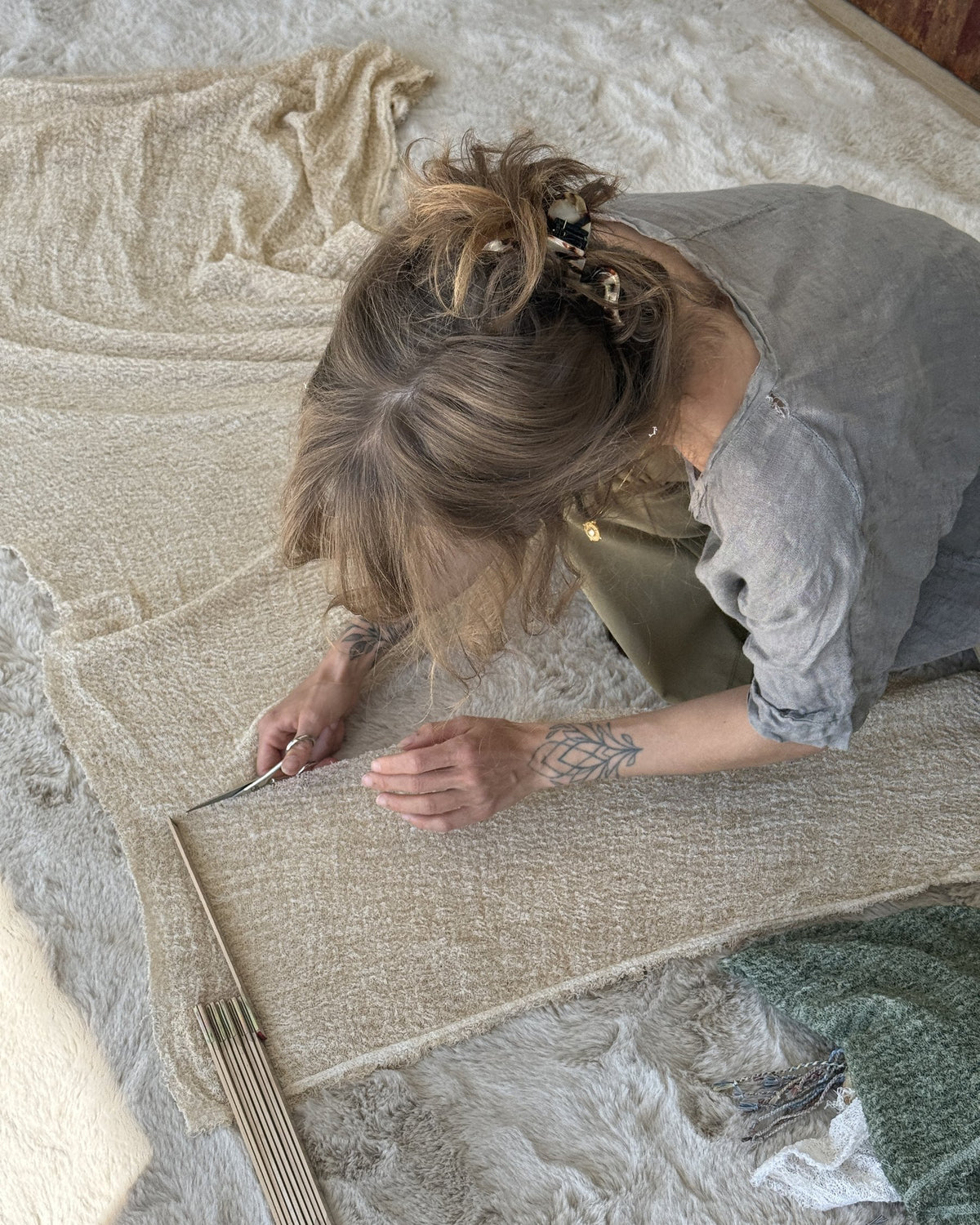 Jamy measuring and cutting fabric samples on the floor at home
