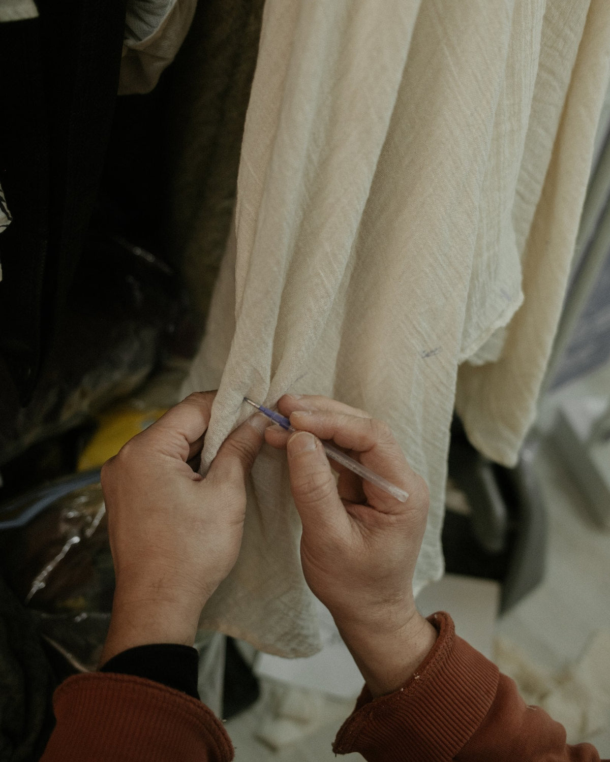 Hands finishing a seam by hand on undyed cotton fabric