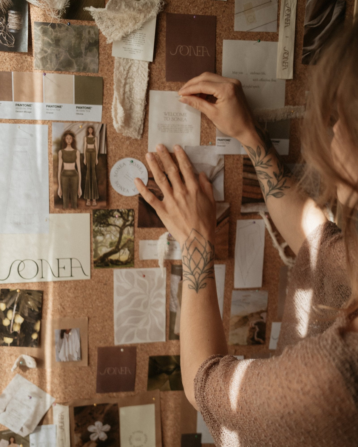 Jamy pinning sketches and swatches to the SONEA vision board in the atelier